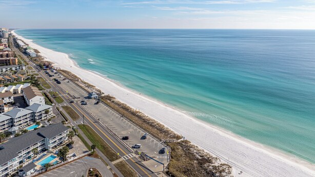 Un hôtel situé sur la côte, avec vue sur la plage, un parking et une route parallèle à la plage.