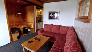 Ein gemütlicher Raum mit einer hölzernen Bank, einem rot gestreiften Sofa und einem Holztisch mit Fernbedienungen.