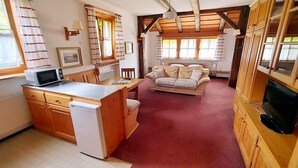 A cozy, open-plan living area with a kitchen, a sofa set, and wooden beams on the ceiling. - Holiday apartment "Hoellfelsen" – 2 Guests (Warmensteinach)