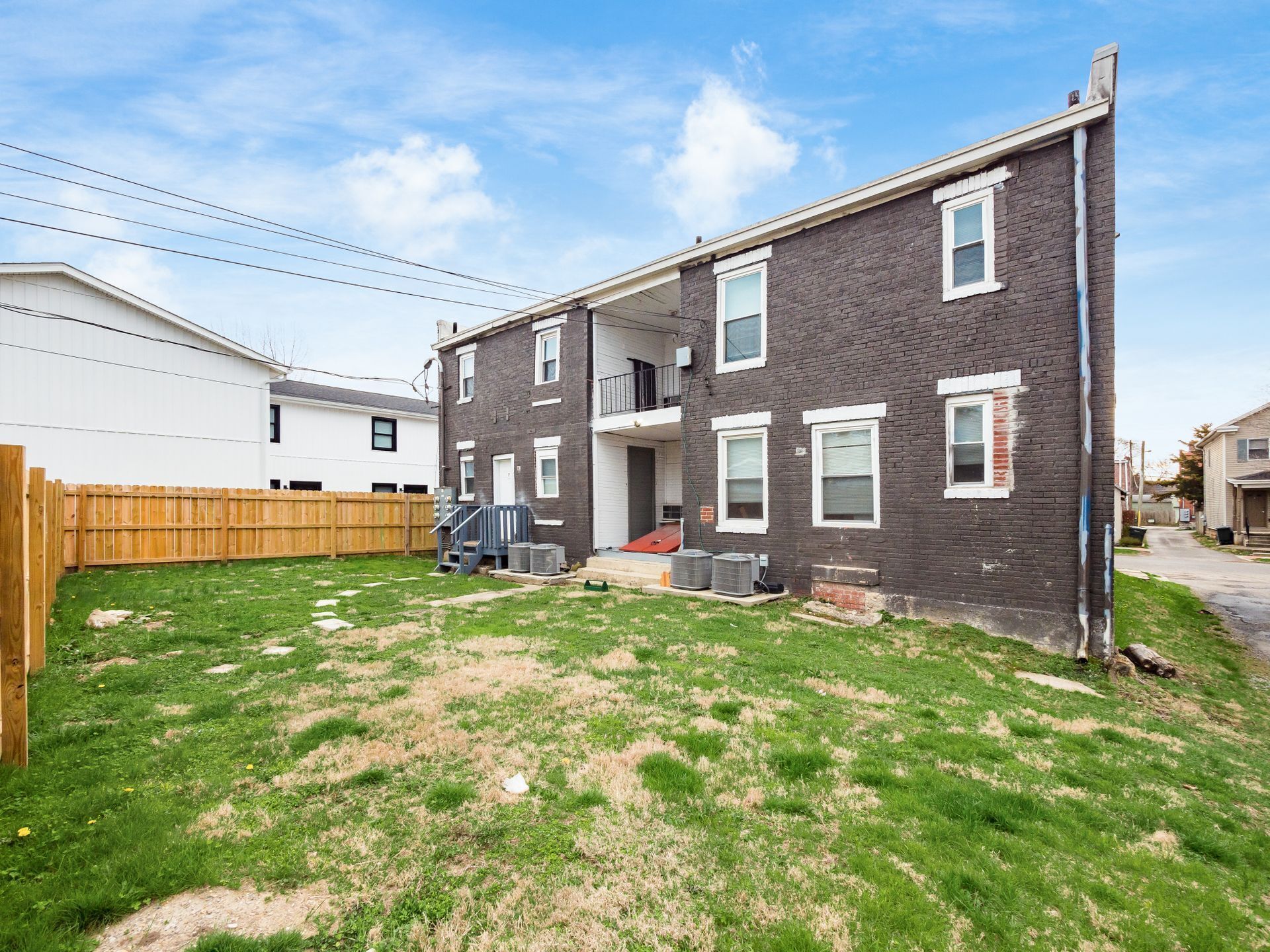 A two-story residential building with a brick exterior and white trim around the windows.