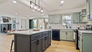 A spacious kitchen with a large island, modern appliances, and ample natural light. - Stylish Bungalow. Sleeps 6. Wi-fi. Pets welcome. (Oklahoma City)