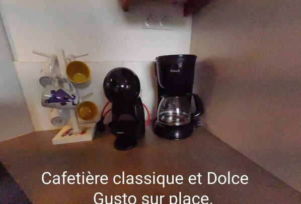 A kitchen with a coffee maker, a kettle, and a coffee pot on the counter.