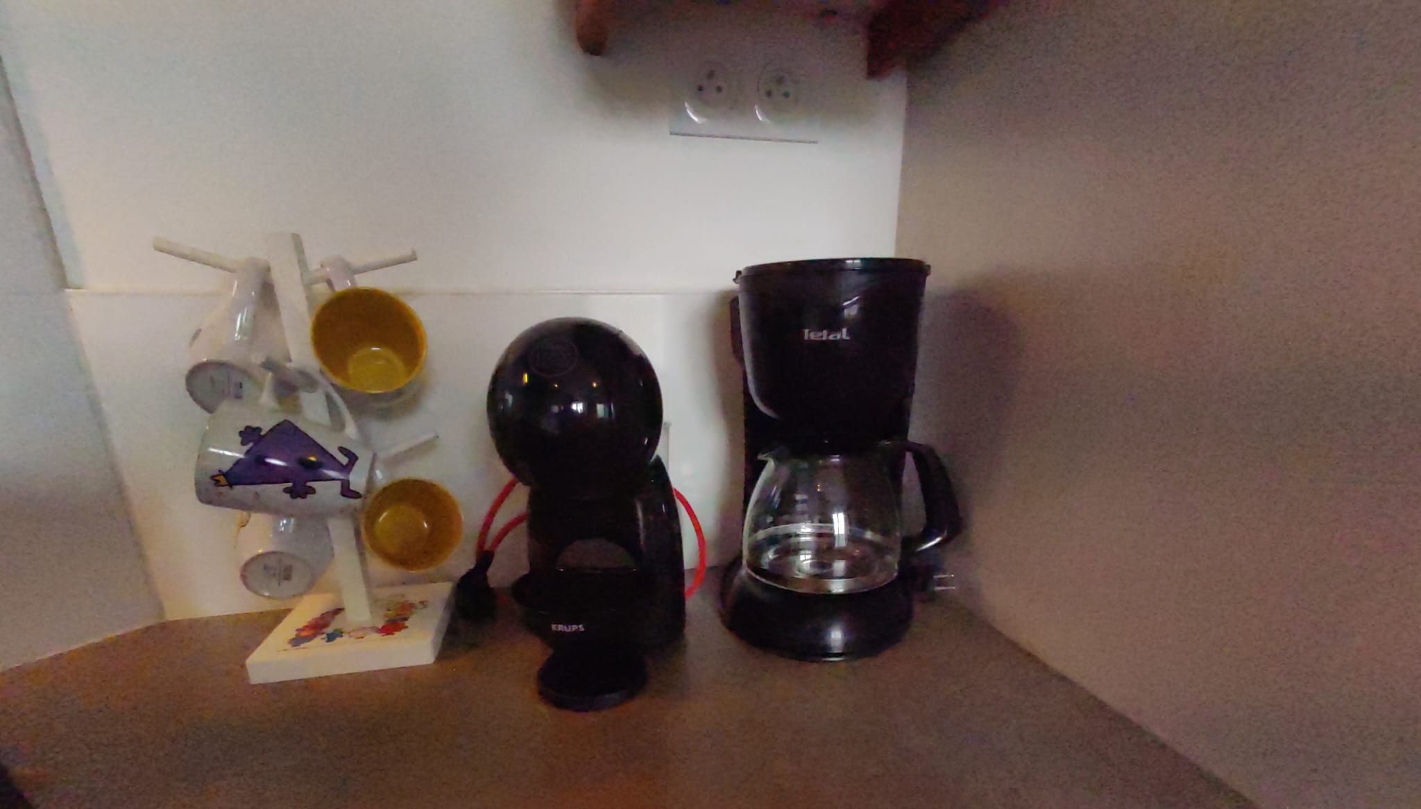 Une cuisine équipée d’une machine à café, d’une bouilloire et d’une cafetière sur le plan de travail.