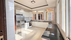 A modern kitchen with white cabinets, stainless steel appliances, and a black countertop. - Mu Rugo by Iwacu Stays (Kigali)