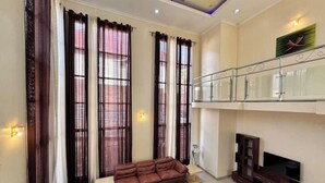 A living room with a sofa, a TV stand, and a balcony with a railing. - Mu Rugo by Iwacu Stays (Kigali)