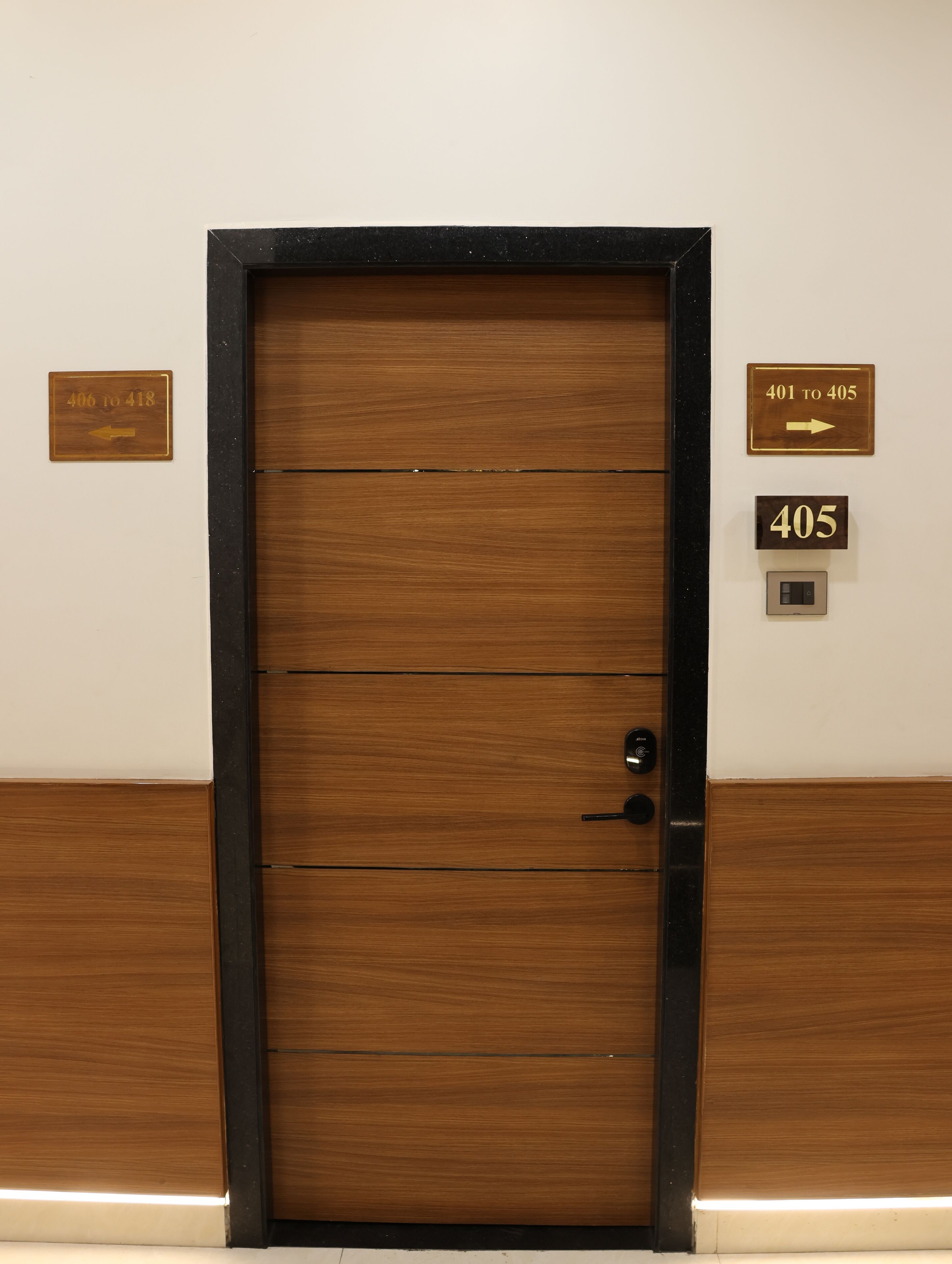A wooden door with a black frame, a room number sign, and a directional sign.