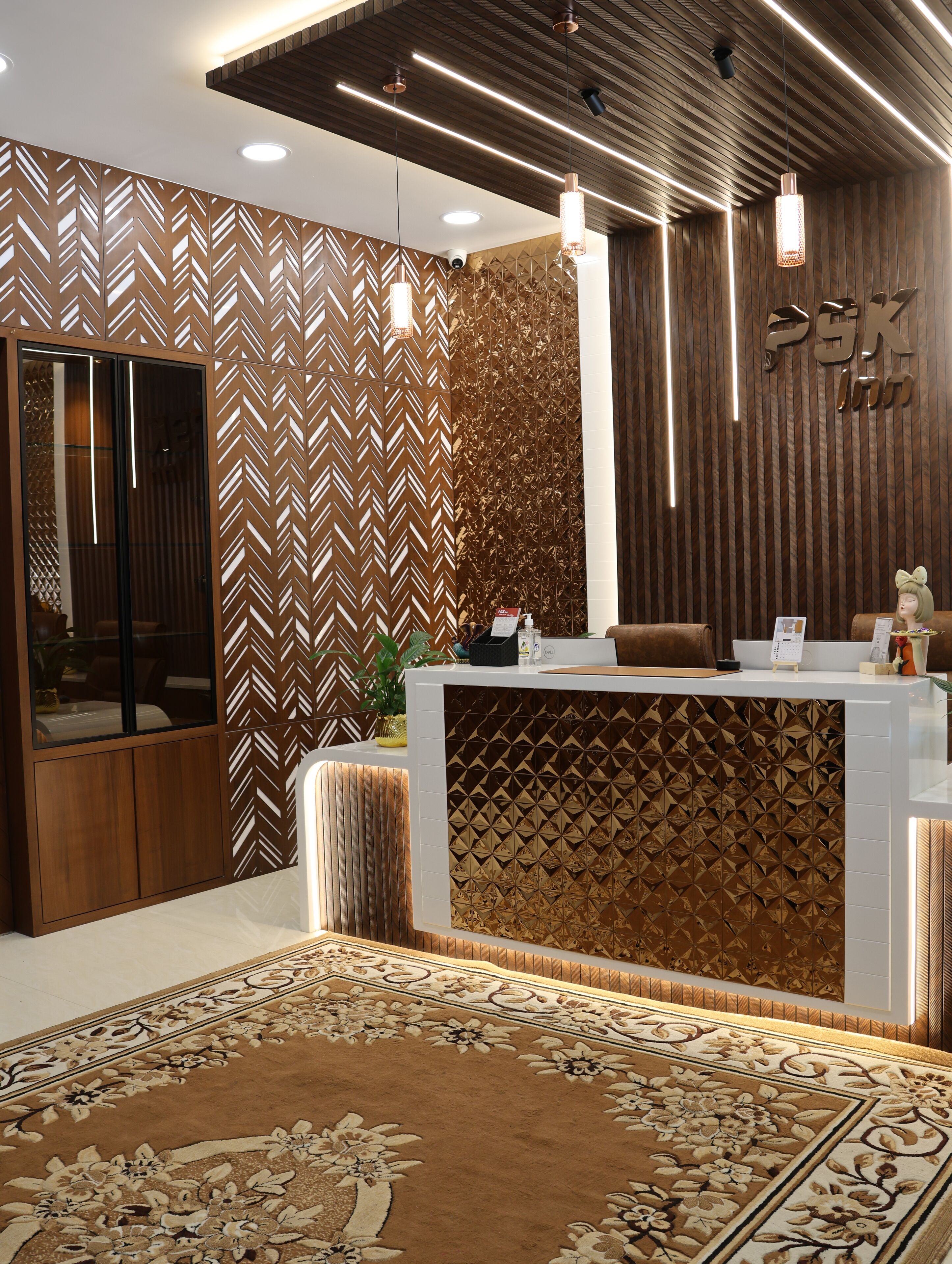 Una zona reception dal design moderno, con un muro decorato da un motivo, una scrivania reception e un tappeto ornamentale.