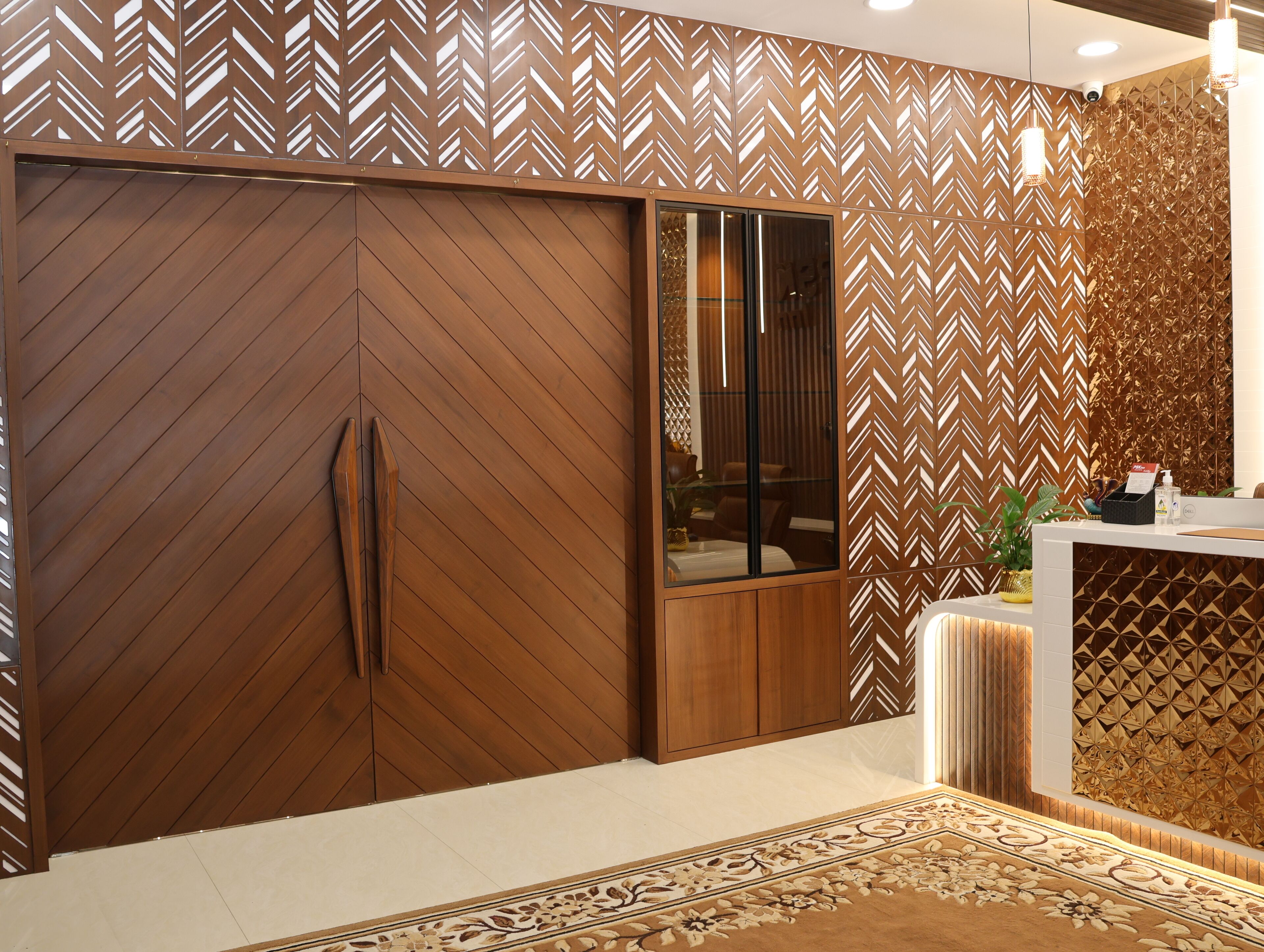 A modern interior with a wooden herringbone-patterned wall, a sliding wooden door, and a reception desk with a patterned rug.