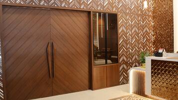 A modern interior with a wooden herringbone-patterned wall, a sliding wooden door, and a reception desk with a patterned rug.