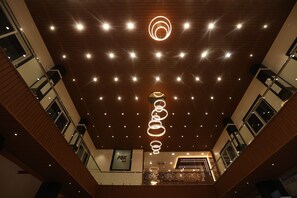 A multi-level hotel interior with a wooden ceiling, multiple floors, and a central staircase. - PSK INN  (Nellore)