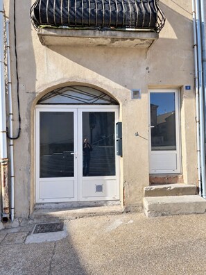 A building with a large arched entrance, a small window, and a door with a glass panel.