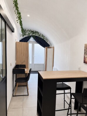 Een moderne, minimalistisch ingerichte kamer met een houten bureau, zwarte stoelen en een groot raam.