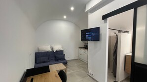 A compact bedroom with a bed, a desk, a TV, and a shower area. - Pleasant studio in the heart of town. Close to the A9 and tramway! (Saint-Jean-de-Védas)