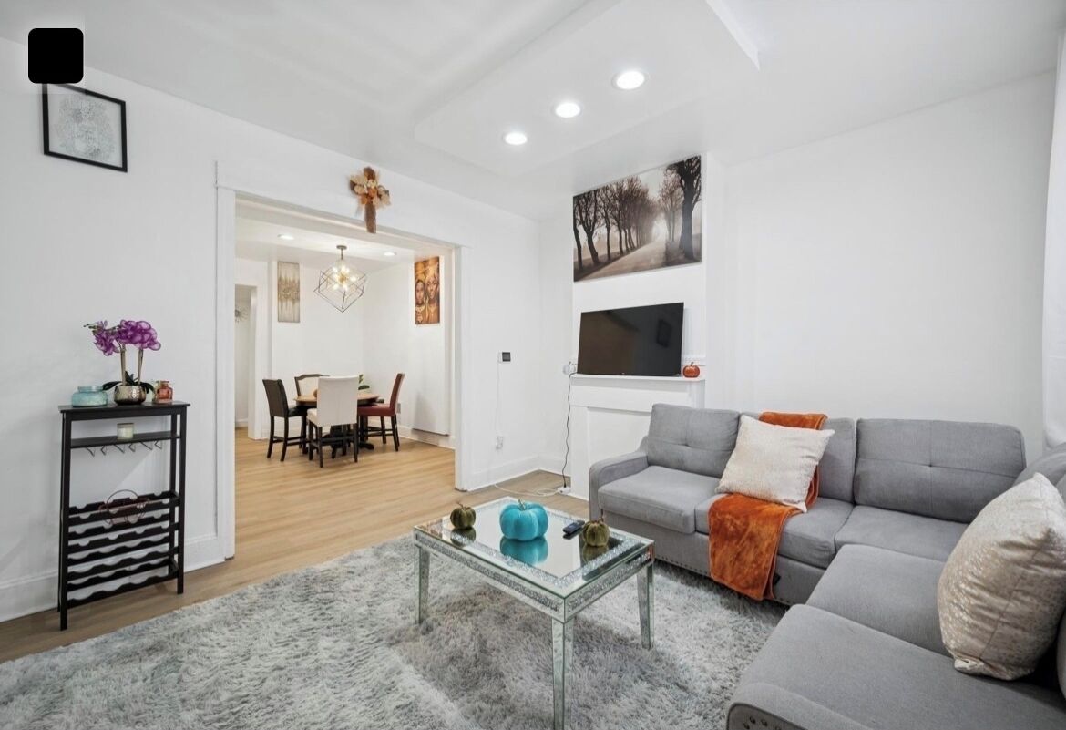 Una sala moderna con un sofá gris, una mesa de centro de cristal y un comedor con mesa y sillas.