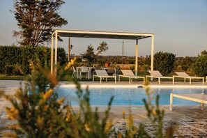 Un espace piscine doté de chaises longues et d’une structure en forme de pergola.