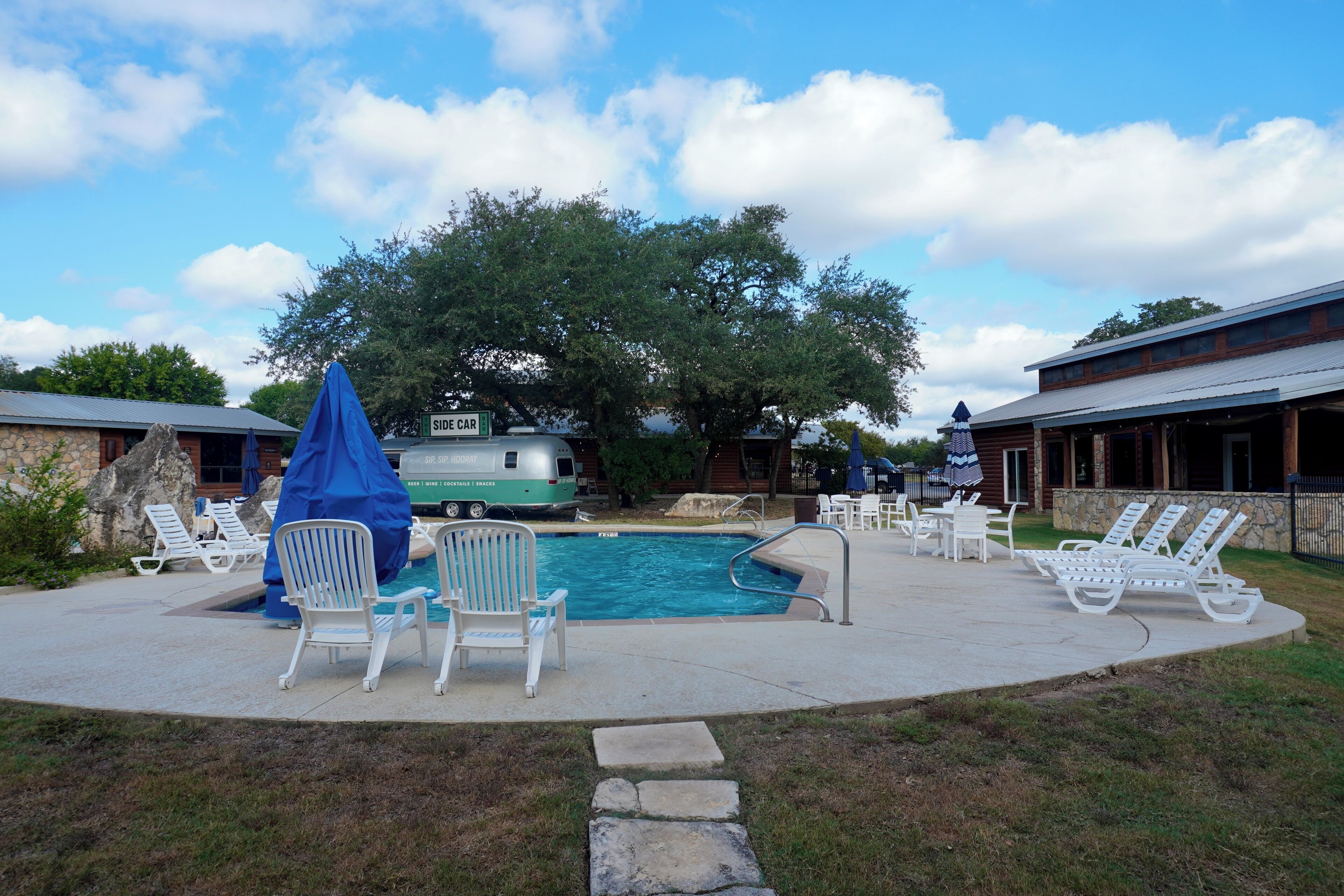 A pool area with lounge chairs and a covered seating area.