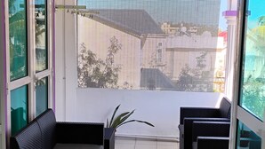Een balkon met een zwarte bank, een klein tafeltje en een plant in een pot.