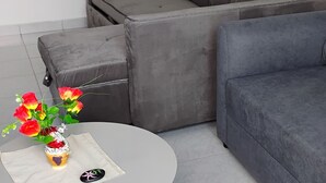 Een moderne woonkamer met een grijze modulaire bank, een witte salontafel met een bloevas en een grijs vloerkleed.