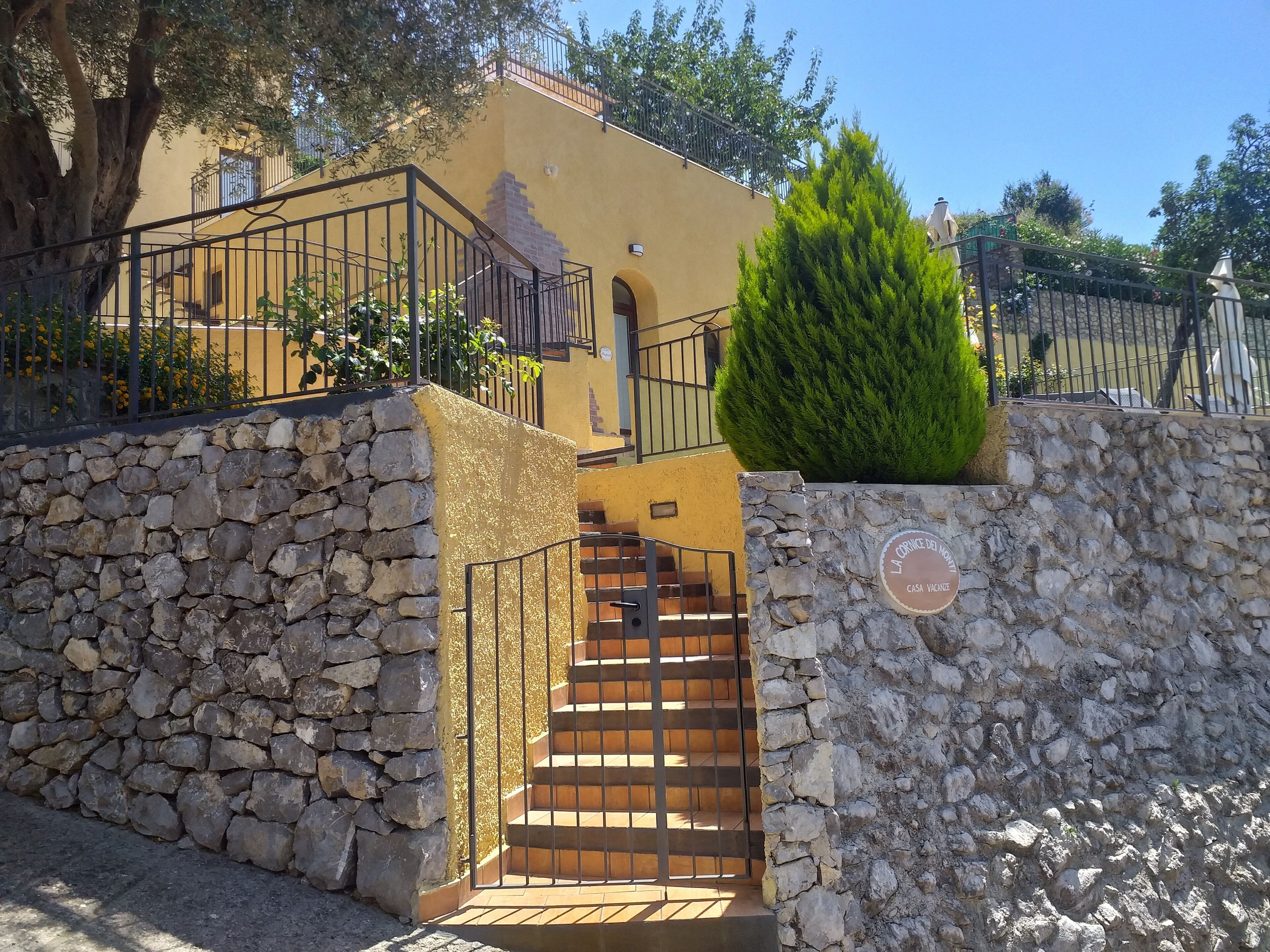 A stone wall with a metal gate leading to a staircase.