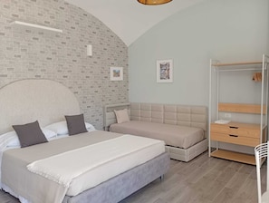 A bedroom with two beds, a wardrobe, and a brick wall. - La Cornice Dei Monti (Tramonti)