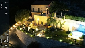 Um pátio bem iluminado com piscina, uma parede de pedra e um edifício com várias janelas e varanda.