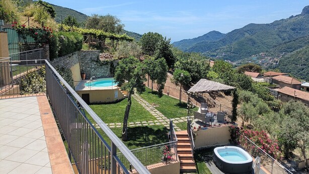 Uma área de piscina com hidromassagem, um muro de pedra e vista para as colinas ao redor.