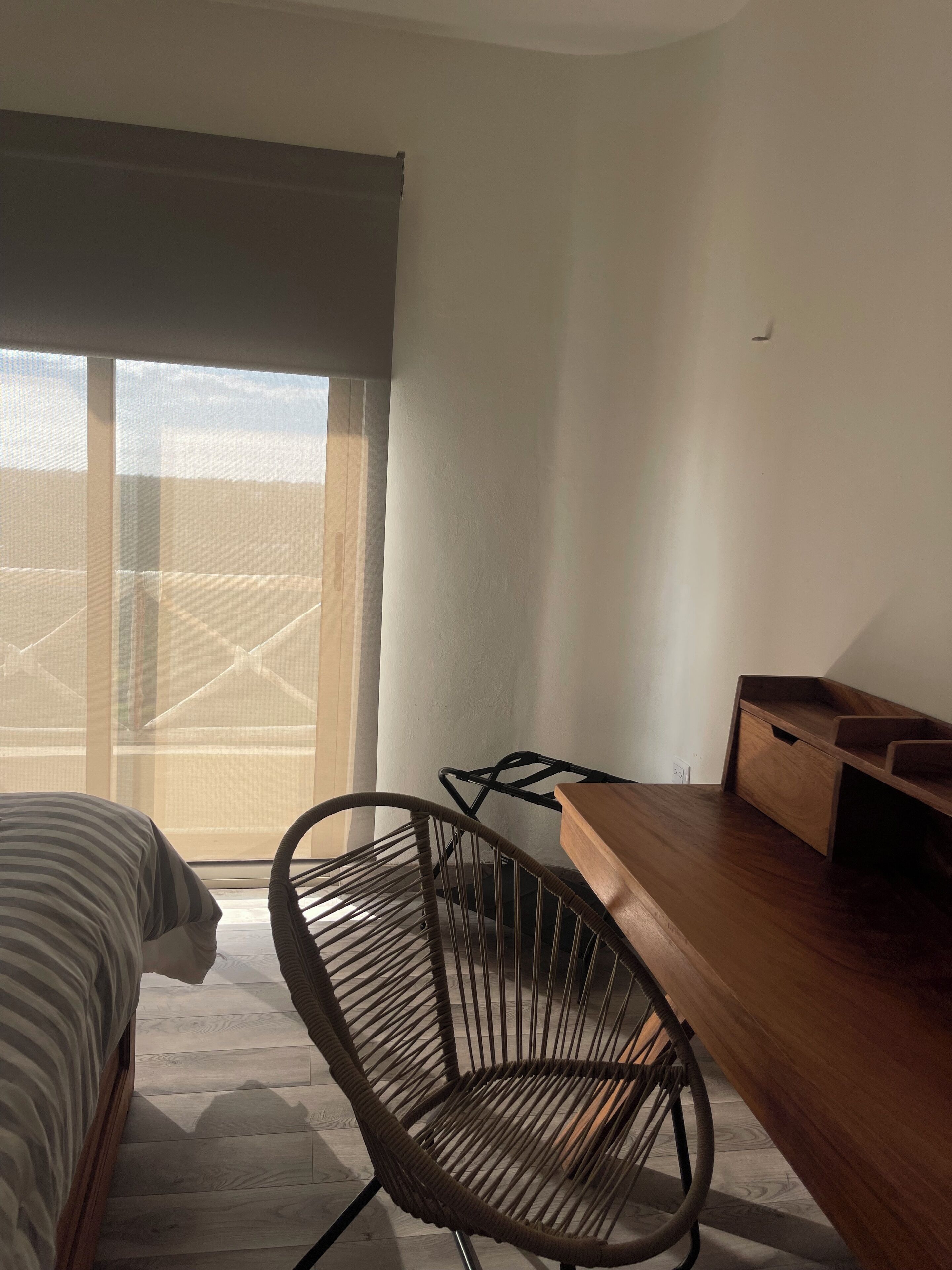 Une pièce comprenant un lit, une chaise, un bureau et une grande fenêtre.