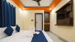 A hotel room with a bed, a TV mounted on the wall, and a door with a handle. - Minx Hotels Radhika Palace (Ayodhya)