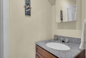 Une salle de bain avec un lavabo blanc, un meuble-lavabo en bois et une serviette accrochée au mur.