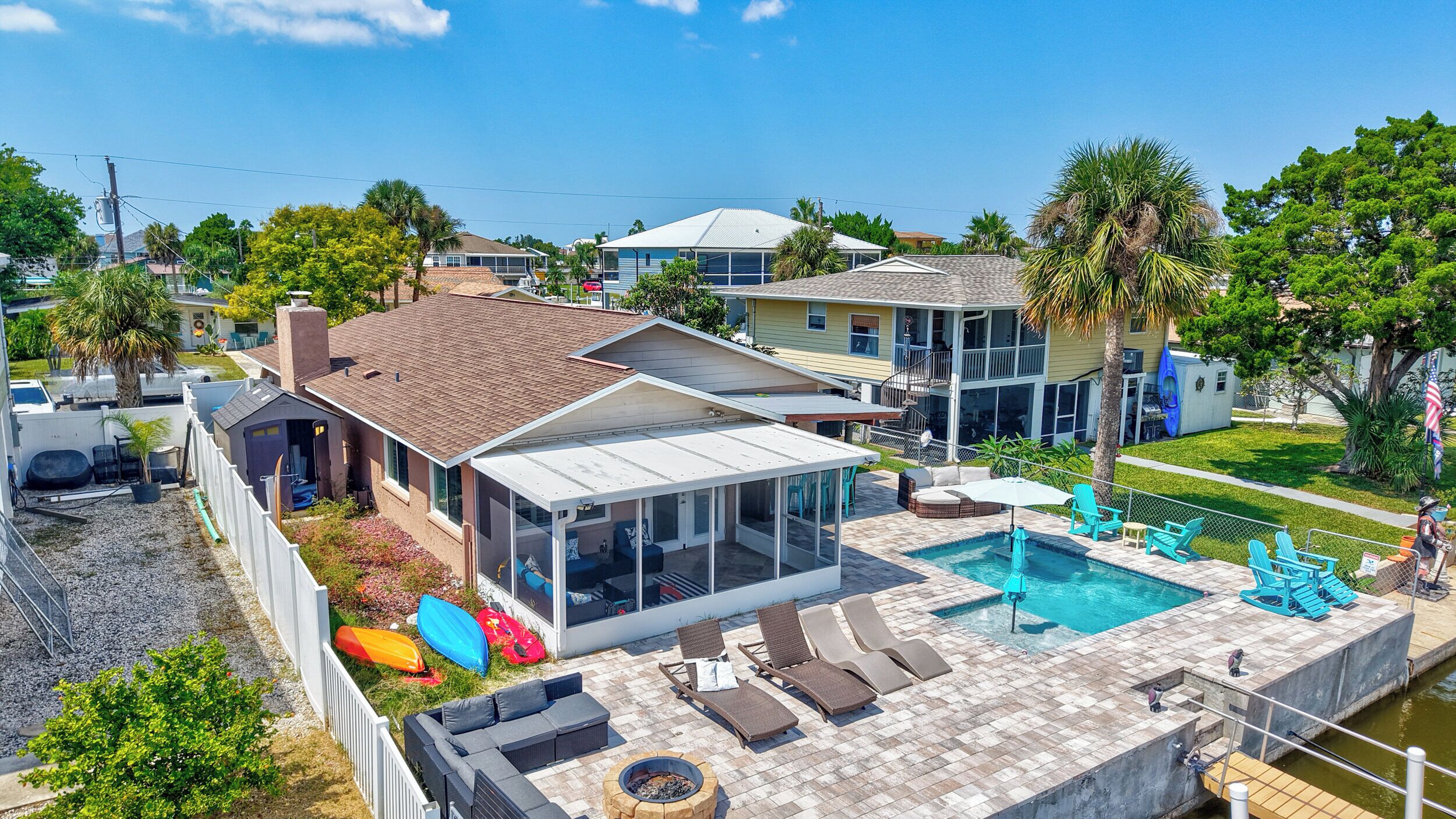 A residential property with a swimming pool, outdoor seating, and a covered patio.