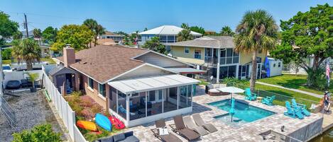 A residential property with a swimming pool, outdoor seating, and a covered patio.