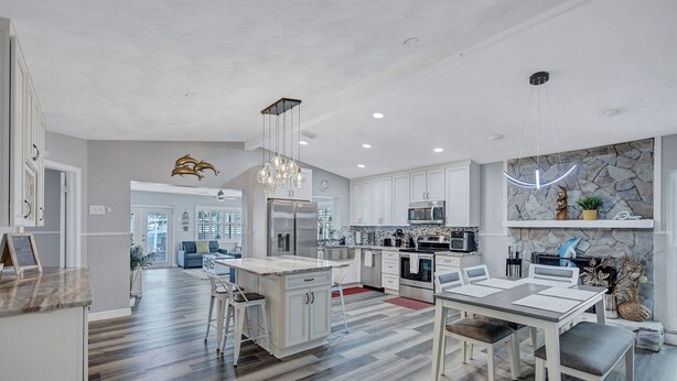 A modern kitchen with white cabinetry, a central island, and pendant lighting. - Hernando Beach Gulf Access, Dock & Heated Pool (Hernando Beach)