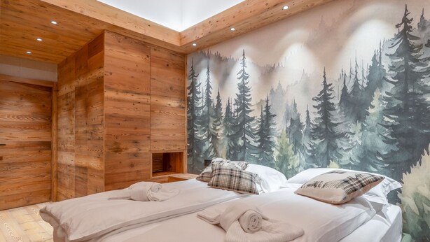 Une chambre avec deux lits, des murs en bois et une fresque représentant une forêt.