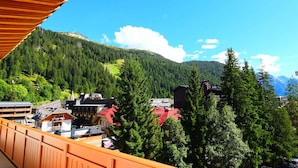Un balcon offrant une vue sur un paysage montagneux, des bâtiments et des arbres.