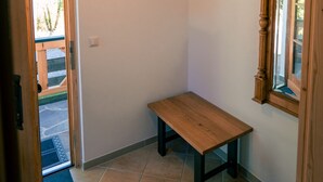A hallway with a wooden bench, a coat rack, a ceiling light, and a door leading outside. - Haus Luise - Cozy vacation apartment with mountain views (Bayrischzell)