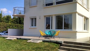 A modern building with a balcony, large windows, and a grassy lawn.
