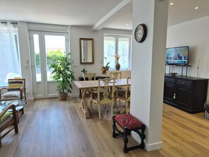 A dining area with a wooden table and chairs, a potted plant, and a television on a cabinet. - A beautiful and very spacious two-bedroom apartment in Bretteville-sur-Odon, in the Venoix neighborhood of Caen. (Bretteville-sur-Odon)