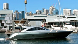 A modern yacht docked at a marina with a city skyline in the background. - Gorgeous 2-bed Unit Near Riverside Parks (Sydney)