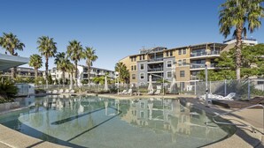 A swimming pool with lounge chairs and palm trees, surrounded by multi-story buildings. - Gorgeous 2-bed Unit Near Riverside Parks (Sydney)