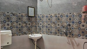 A small bathroom with a toilet, sink, and a water heater mounted on the wall. - Home of Lavenia (Rishikesh)