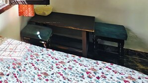 A room with a bed, a bench, a wall-mounted shelf with a plant, and framed pictures. - Home of Lavenia (Rishikesh)