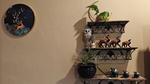 A wall with a circular painting, three shelves with decorative items, and a potted plant. - Home of Lavenia (Rishikesh)