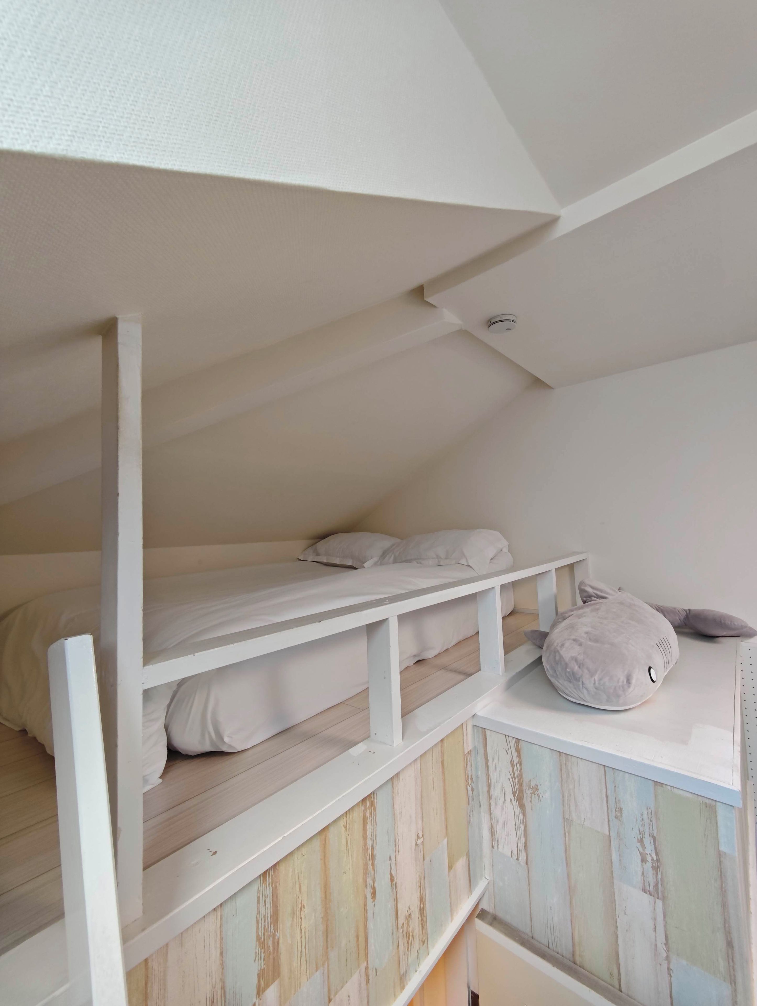 A bunk bed with white bedding and a small plush toy on the top bunk.