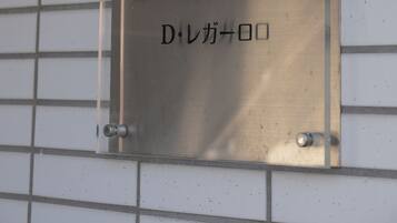 Una placa metálica con el texto "D. Regar" y caracteres japoneses sobre una pared de azulejos.