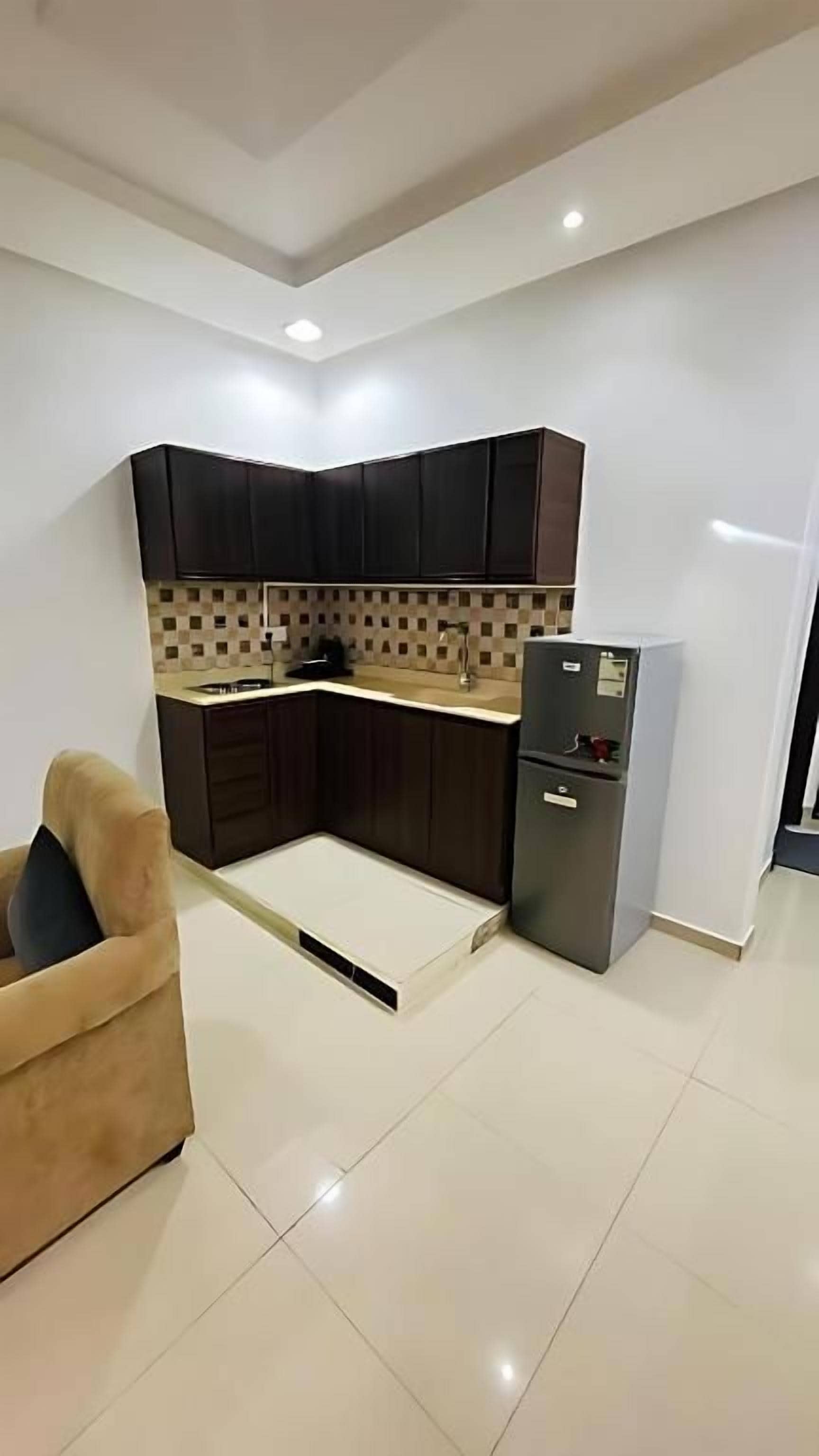 Una cocina compacta con armarios oscuros, horno empotrado y refrigerador.