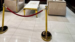 A hotel lobby with a large flat-screen TV, two sofas, a coffee table, and a red rope barrier. - Razan Home 1 for serviced apartments (Riyadh)