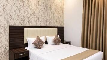 Una habitación de hotel con una cama grande, una mesita de noche y un cabecero con un diseño tipo mármol.
