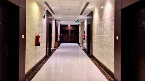 A modern hotel corridor with marble walls, a shiny tiled floor, and dark wooden doors. - Razan Home 1 for serviced apartments (Riyadh)