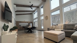 A spacious living area with a large window, a ceiling fan, and a cozy seating arrangement. - OFF-PISTE VBN - LUXURY - MODERN - SPA (St-Raymond)
