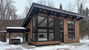 A modern two-story building with large windows and a wooden facade, surrounded by snow. - OFF-PISTE VBN - LUXURY - MODERN - SPA (St-Raymond)